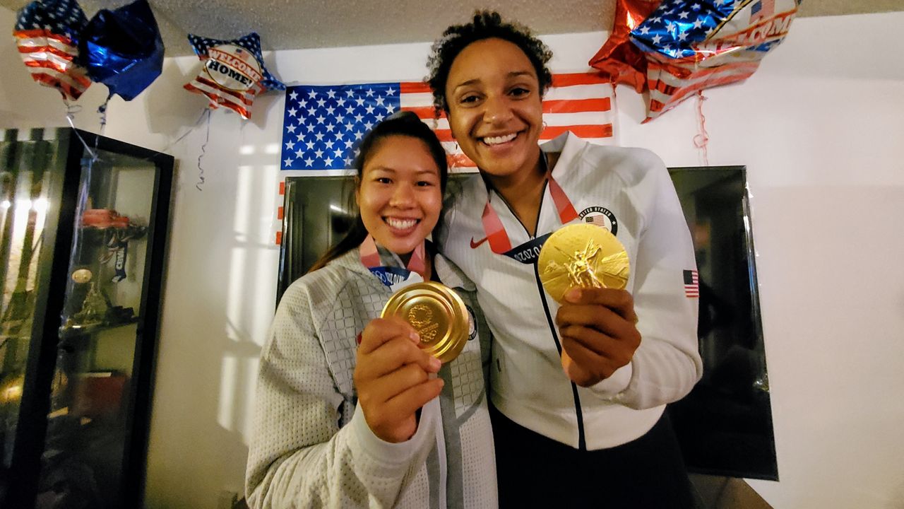 U.S. women's volleyball players Justine Wong-Orantes and Haleigh Washington show off their gold medal during a family celebration in Cypress, Calif. (Spectrum News/Joseph Pimentel)