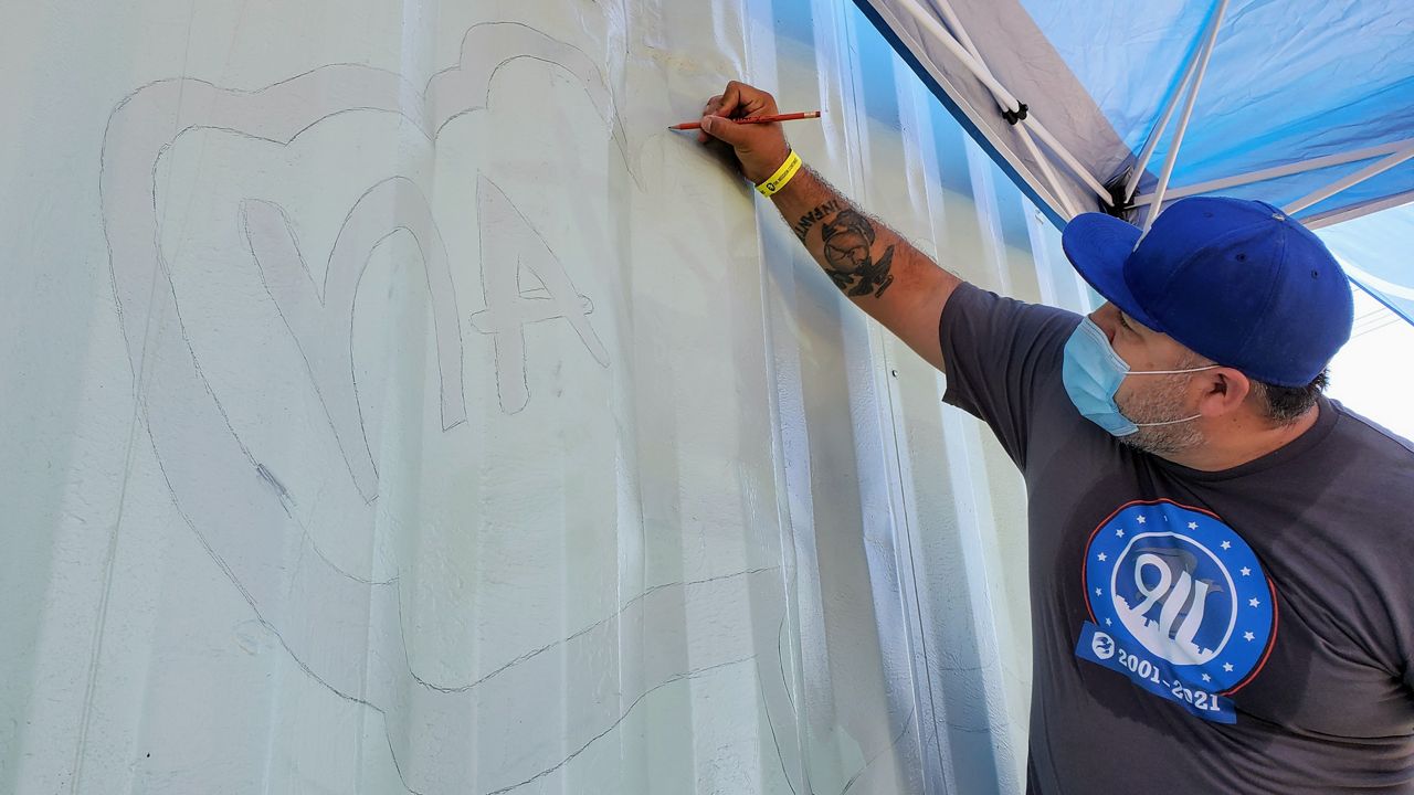 Former Marine Josue Guerrero outlines a mural on a storage container at the Wanda A. Mikes Early Education Center in South Los Angeles. (Spectrum News/Joseph Pimentel)