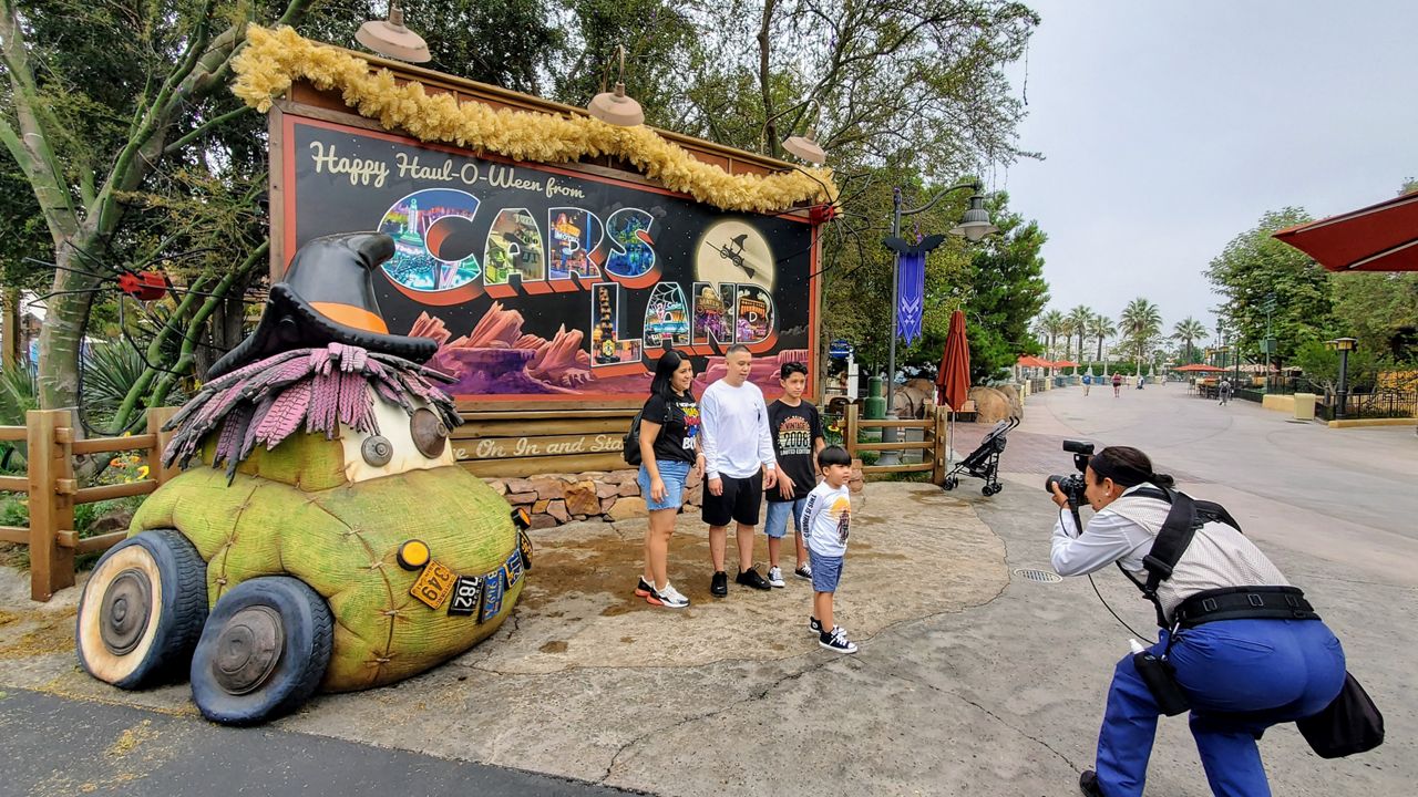 A family takes a picture in front of a Halloween-themed Cars Land sign (Spectrum News/ Joseph Pimentel)