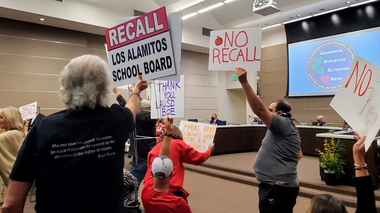 Demonstrators hold up signs during a Los Alamitos Unified School Board meeting in Los Alamitos, Calif. on Tuesday. (Spectrum News/Joseph Pimentel)