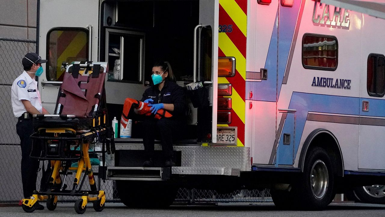 Emergency medical technicians sanitize their ambulance after transporting a patient at Los Angeles County + USC Medical Center in Los Angeles Tuesday, Jan. 5, 2021. Los Angeles continues to see hospitalizations rise day after day, setting a new record Tuesday with almost 8,000 hospitalized and more than a fifth of those in intensive care units.(AP Photo/Damian Dovarganes)