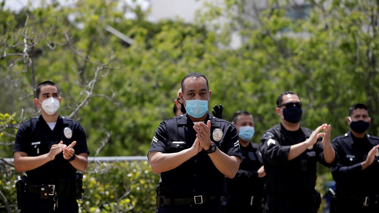 In this April 17, 2020, file photo, members of the Los Angeles Police Department thank hospital workers after an officer was treated and recovered from COVID-19 outside Providence St. John's Medical Center in Santa Monica, Calif. (AP Photo/Marcio Jose Sanchez)