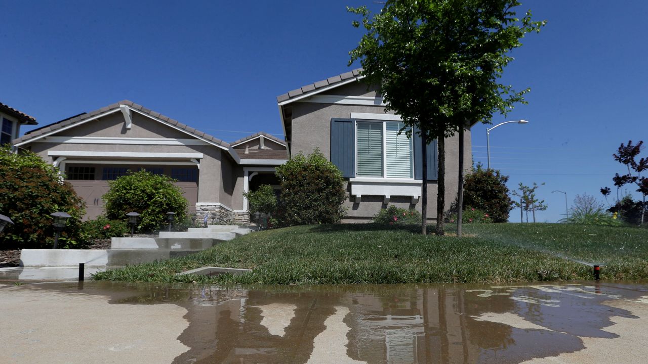 In this April 2, 2015, file photo, water flows down a sidewalk from water sprinklers running at a home in Rancho Cordova, Calif. (AP Photo/Rich Pedroncelli)