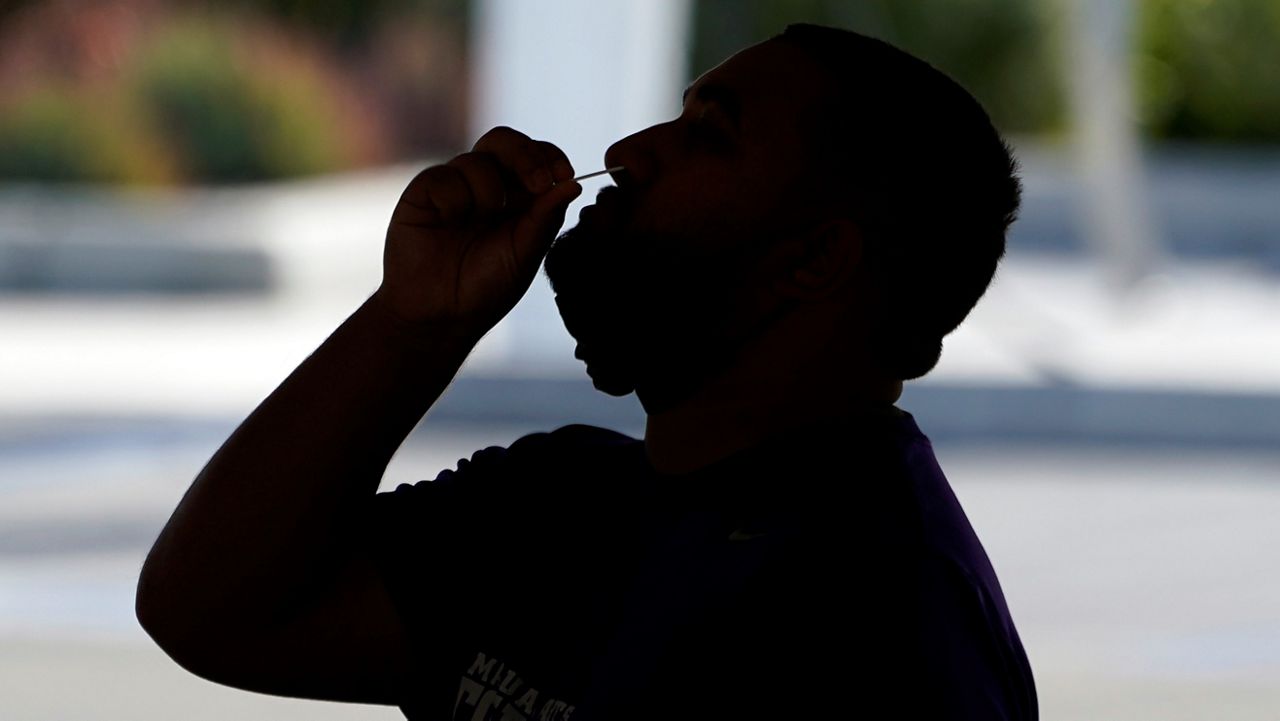 A man swabs his nose at a COVID-19 testing location on Monday at the Martin Luther King Jr. medical campus in Los Angeles. (AP Photo/Marcio Jose Sanchez)