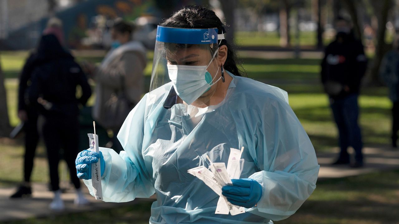 Medical assistant Leslie Powers carries swab samples collected from people Thursday to process them on-site at a COVID-19 testing site in Long Beach, Calif. (AP Photo/Jae C. Hong)