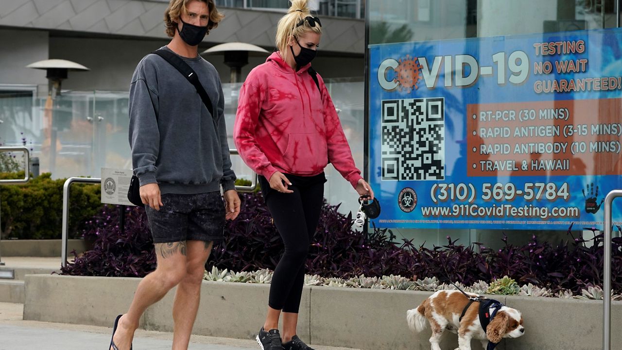 In this May 13, 2021, file photo, visitors walk past a sign advertising COVID-19 testing in Santa Monica, Calif. (AP Photo/Marcio Jose Sanchez)