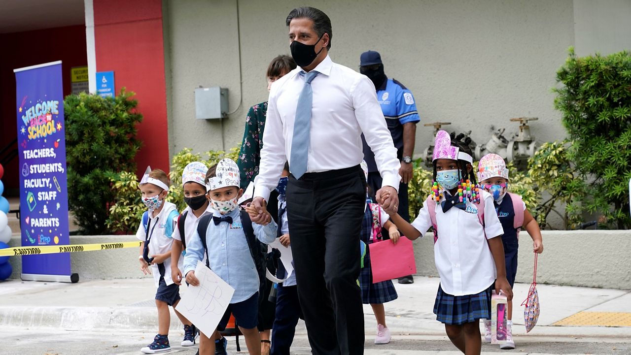 In this Aug. 23, 2021, file photo, then-Miami-Dade schools Superintendent Alberto Carvalho, center, walks with students outside iPrep Academy on the first day of school in Miami. (AP Photo/Lynne Sladky)
