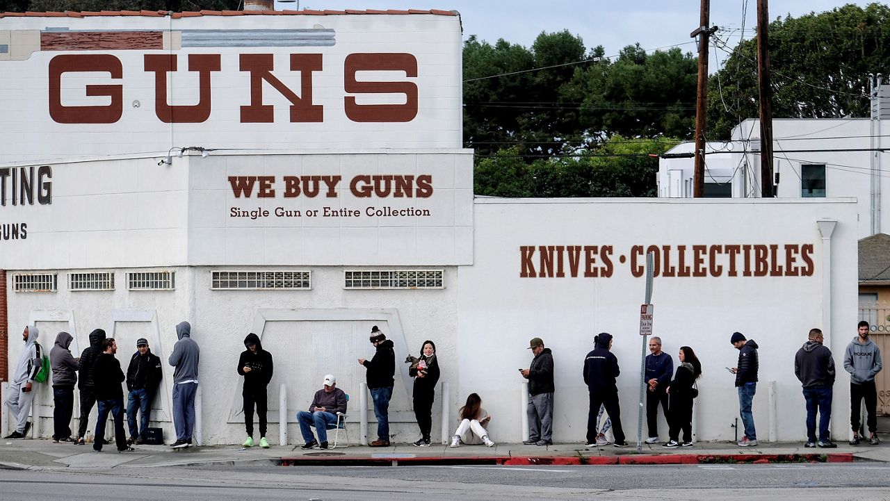In this March 15, 2020, file photo, people wait in a line to enter a gun store in Culver City, Calif. The 9th U.S. Circuit Court of Appeals on Thursday overturned two California counties orders shutting down gun and ammunition stores in 2020 as nonessential businesses during the coronavirus pandemic. (AP Photo/Ringo H.W. Chiu)