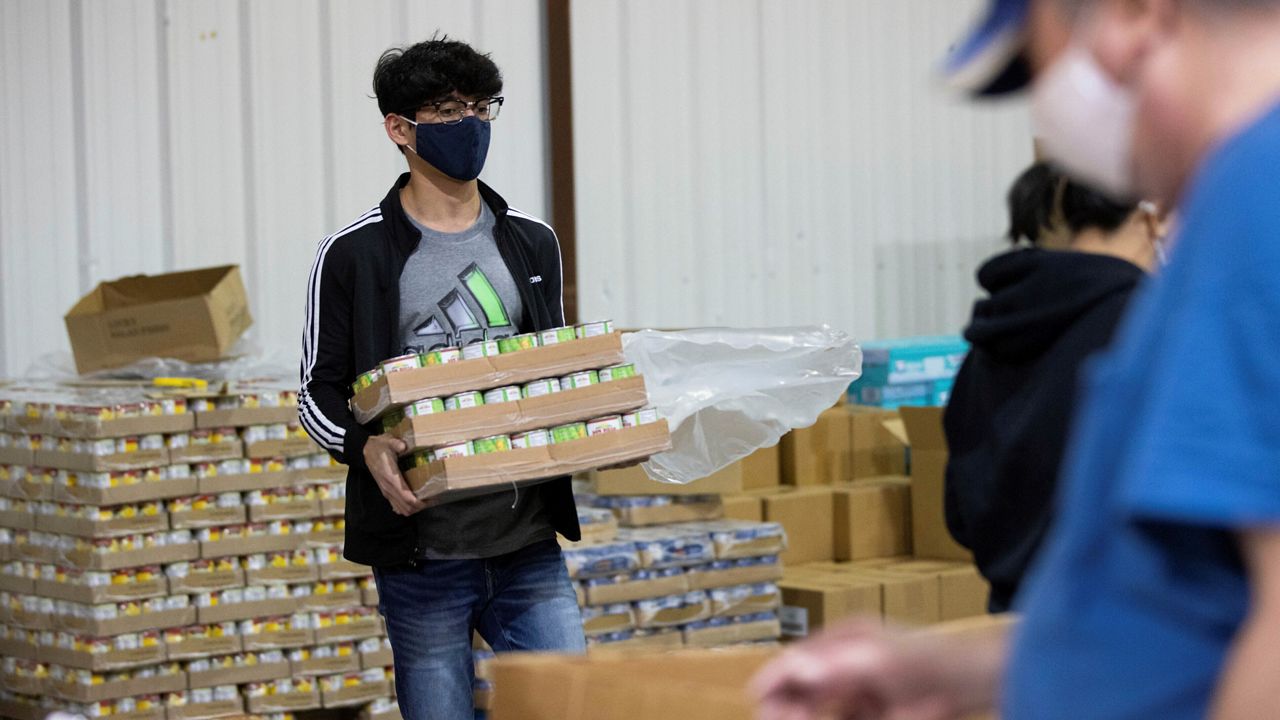 Volunteer Salok Samant carries boxes of canned food for the backpack program at Feeding America food bank Monday in Elizabethtown, Ky. Food banks across the country are experiencing a critical shortage of volunteers as the omicron variant frightens people away from group activities. (AP Photo/Michael Clubb)