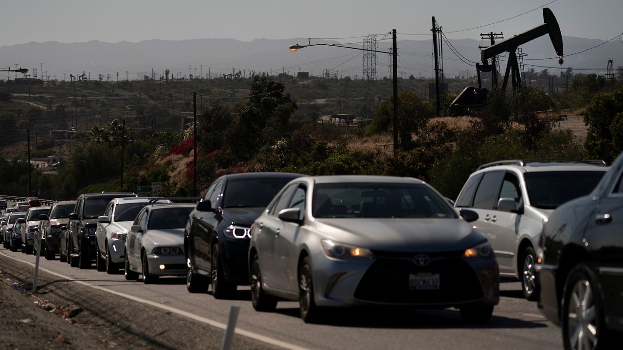 In this June 10, 2021, file photo, motorists wait for a signal to change as pump jacks extract oil at the Inglewood Oil Field in Los Angeles. (AP Photo/Jae C. Hong)