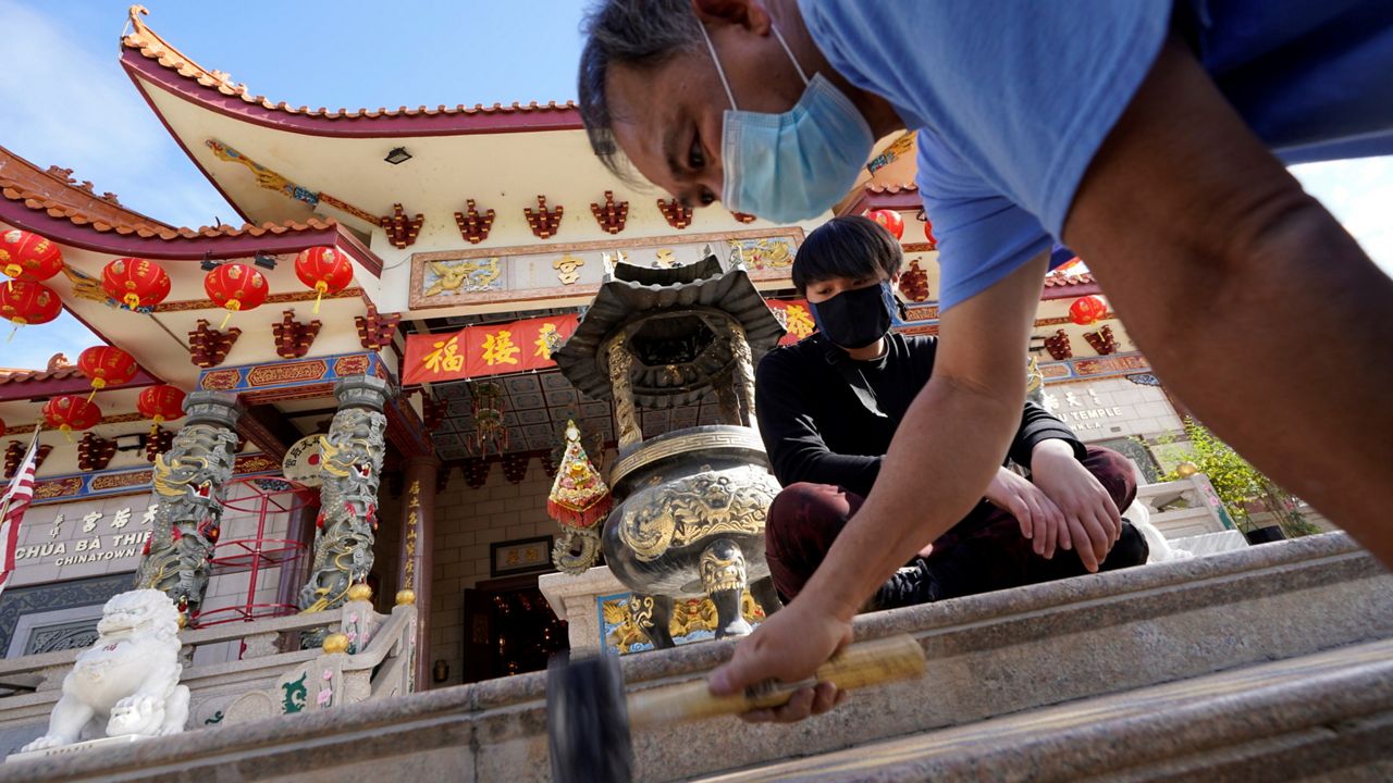Volunteers Alex Koi, foreground, and his son Lipsun Koi, 20, help install anti-slip tape Friday on the front steps of the Thien Hau Temple ahead of the crowds expected for the Lunar New Year of the Tiger celebrations in the Chinatown district of Los Angeles. (AP Photo/Damian Dovarganes)