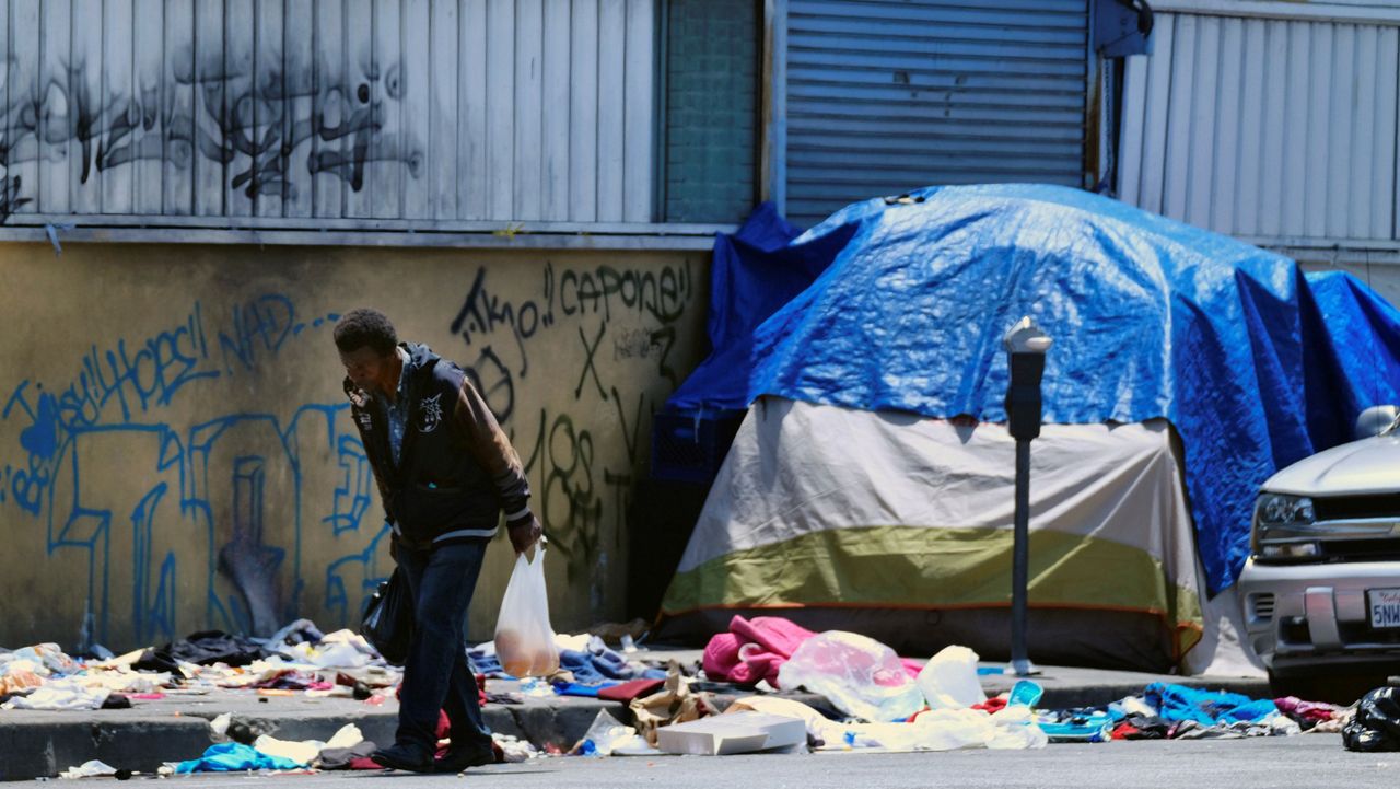 In this May 30, 2019, file photo, a homeless man walks along a street lined with trash in downtown Los Angeles. (AP Photo/Richard Vogel)