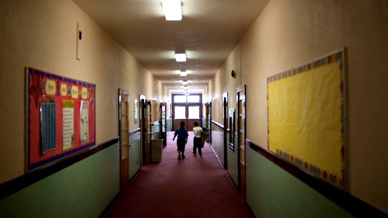 This July 18, 2012, photo shows students wandering down the halls of Our Lady of Lourdes during summer school in Los Angeles. (AP Photo/Grant Hindsley)