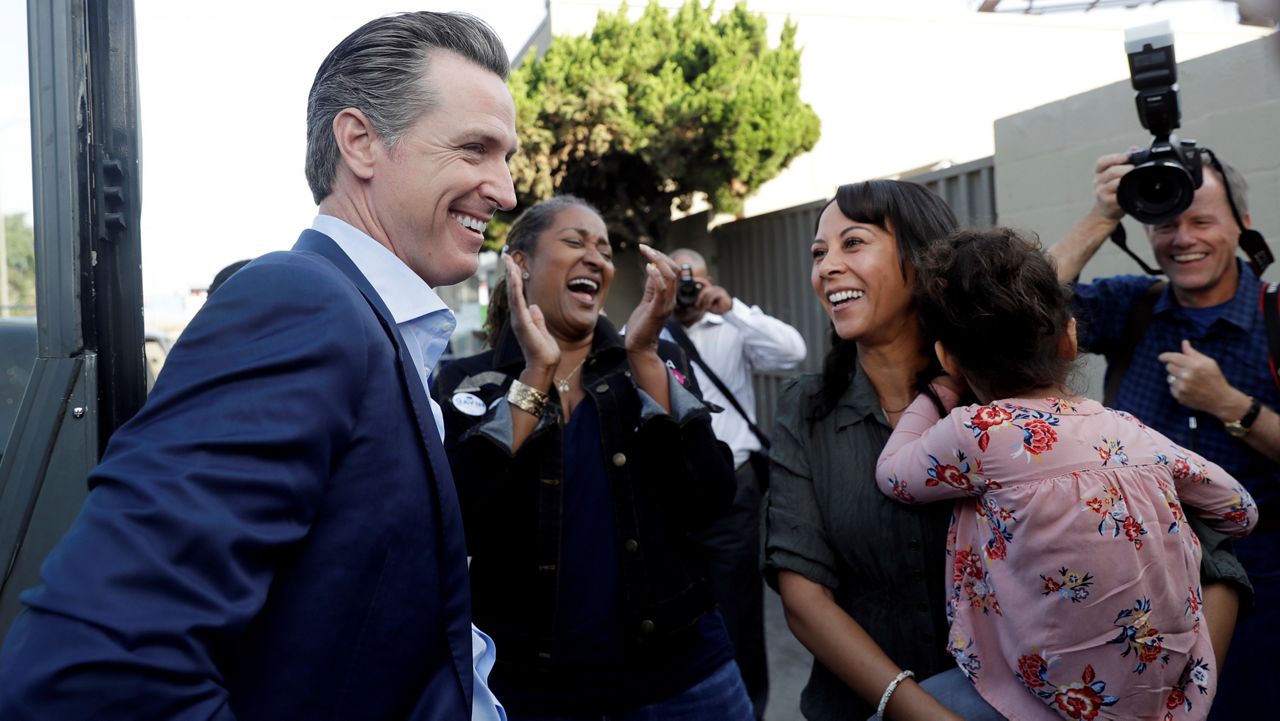 In this Nov. 5, 2018, file photo, California gubernatorial Democratic candidate Gavin Newsom, left, laughs with State Sen. Holly Mitchel, center, and assemblywoman Autumn Burke, right, D-Los Angeles, during a campaign stop at CJ's Cafe in Los Angeles. (AP Photo/Marcio Jose Sanchez)