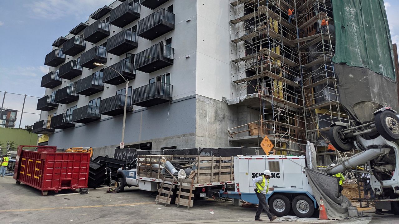 In this June 18, 2021, file photo, construction workers finish the exterior of an apartment building downtown Los Angeles. (AP Photo/Damian Dovarganes)