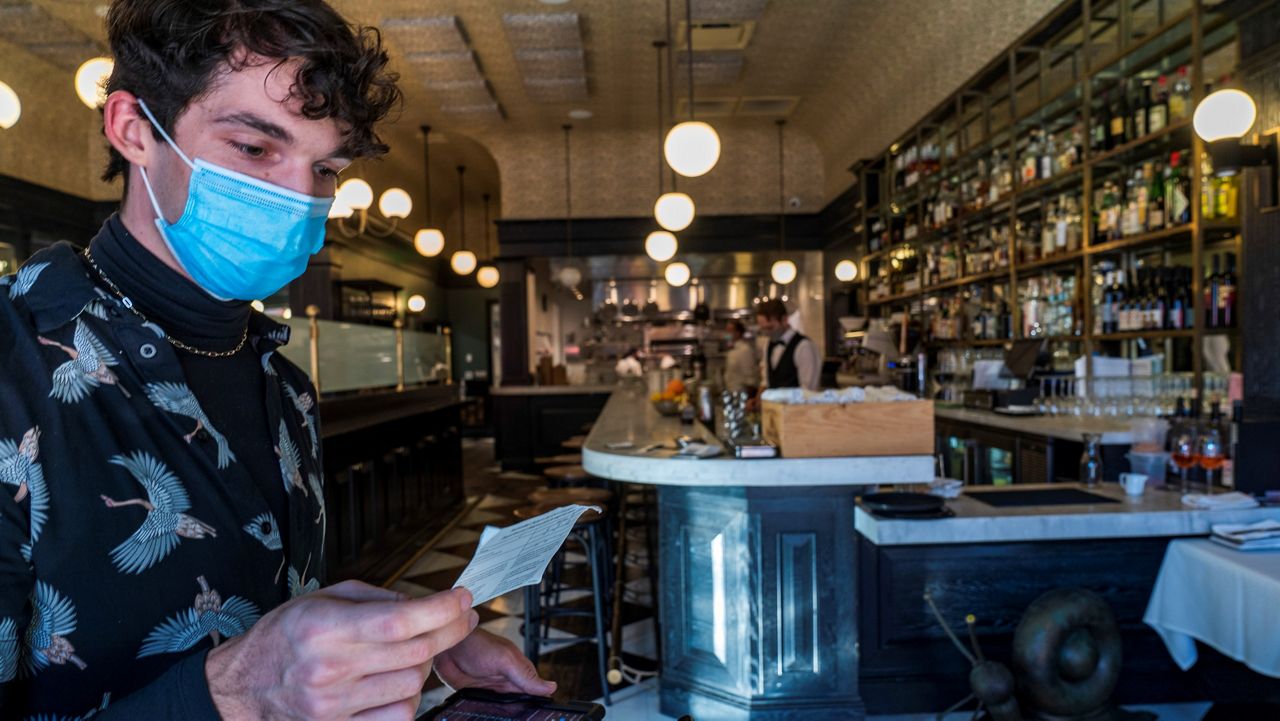 In this Nov. 5, 2021, file photo, restaurant host Joey Tyler verifies a patron’s vaccination card at French restaurant Petit Trois in Los Angeles. (AP Photo/Damian Dovarganes)