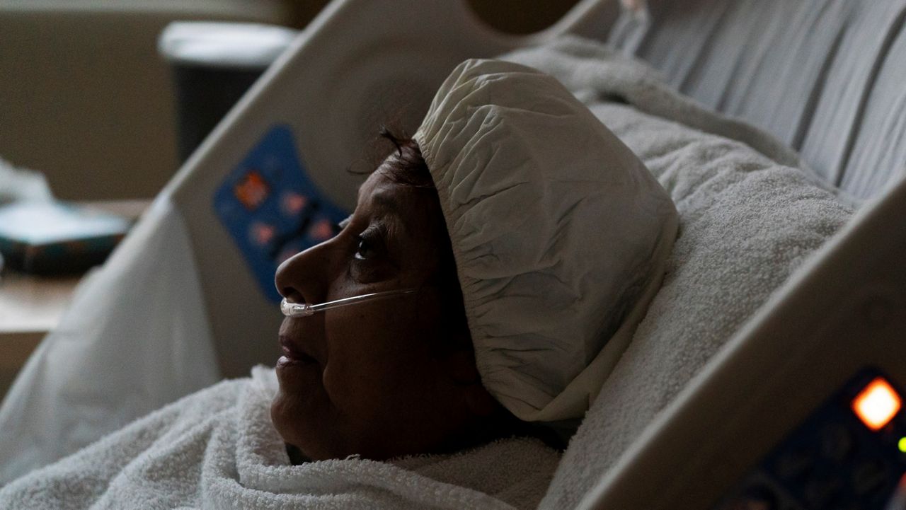 In this Dec. 13, 2021, file photo, Natalie Balli, 71, watches TV while being treated in a COVID-19 unit at Providence Holy Cross Medical Center in Los Angeles. (AP Photo/Jae C. Hong)