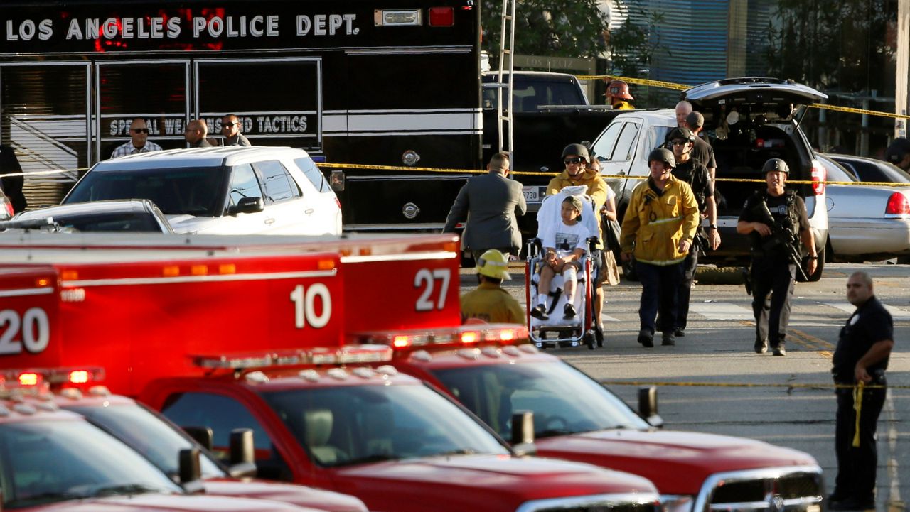 In this July 21, 2018, file photo, Los Angeles Police SWAT officers, and Los Angeles firefighters wearing bulletproof helmets, evacuate a child, after a gunman barricaded himself inside a Trader Joe’s store in Los Angeles. (AP Photo/Damian Dovarganes)