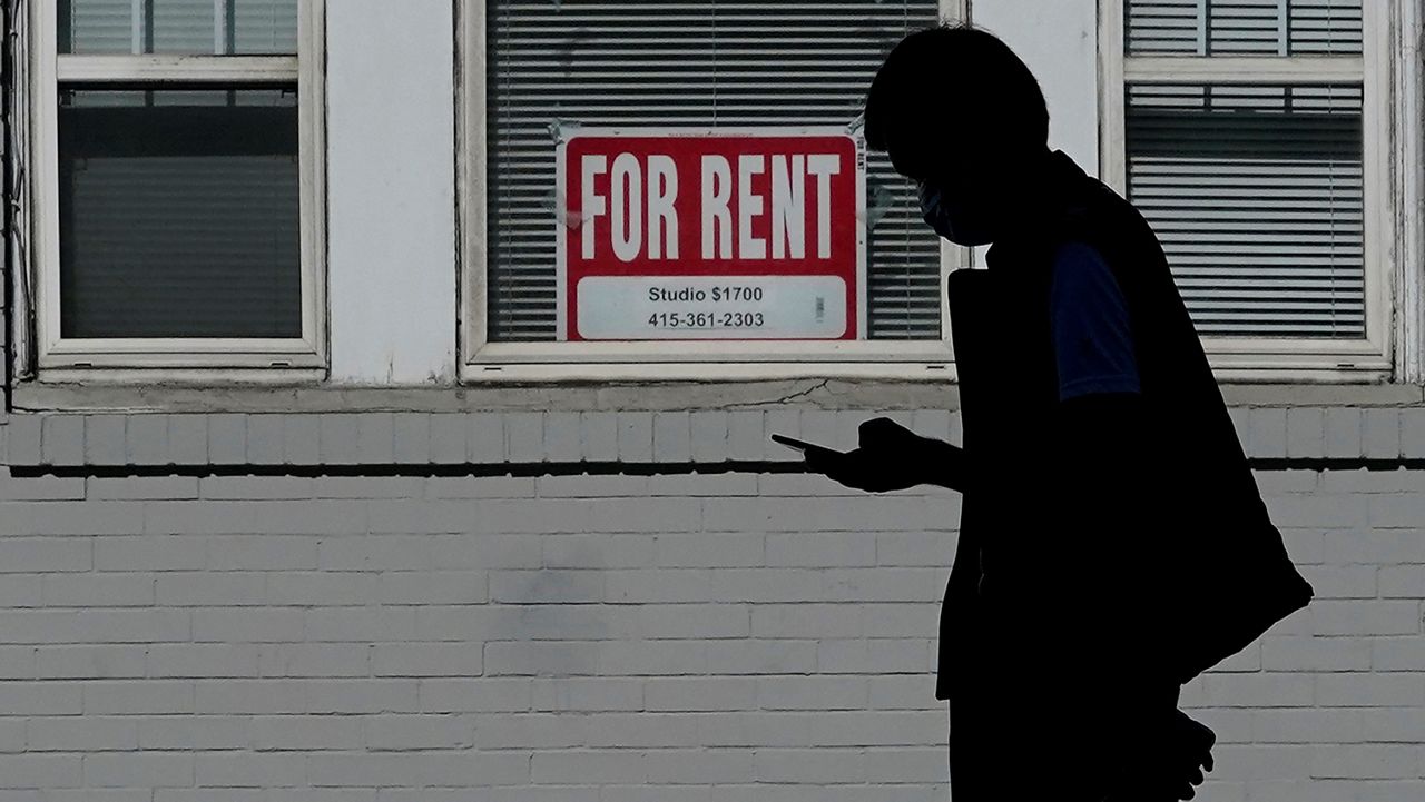 In this Oct. 20, 2020 file photo, a man walks in front of a For Rent sign in a window of a residential property in San Francisco. (AP Photo/Jeff Chiu, File)