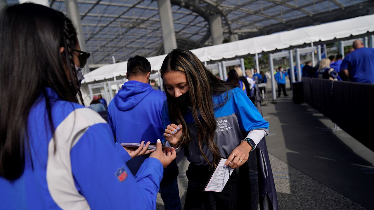 In this Dec. 5, 2021, file photo, a worker checks proof of vaccination as fans enter SoFi Stadium amid the COVID-19 pandemic before an NFL football game between the Los Angeles Rams and the Jacksonville Jaguars in Inglewood, Calif. (AP Photo/Jae C. Hong)