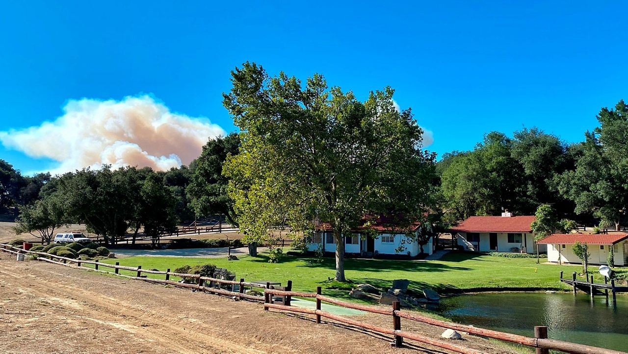 In this Oct. 12, 2021, photo provided by Santa Barbara County Fire, a smoke column builds in the distance behind former President Ronald Reagan’s Rancho del Cielo in Santa Barbara County, Calif. (Mike Eliason/Santa Barbara County Fire via AP)