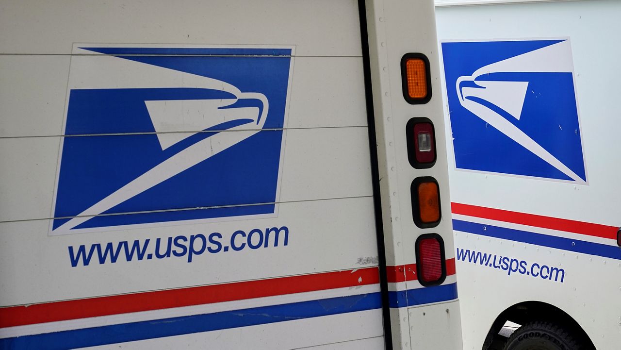 In this Aug. 18, 2020, file photo, mail delivery vehicles are parked outside a post office in Boys Town, Neb. (AP Photo/Nati Harnik)