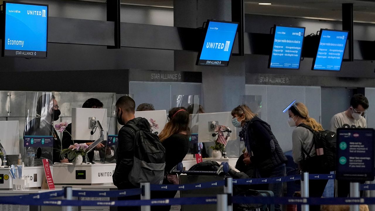 In this Nov. 24, 2020, file photo, travelers check in at United desks at San Francisco International Airport during the coronavirus outbreak in San Francisco. (AP Photo/Jeff Chiu)