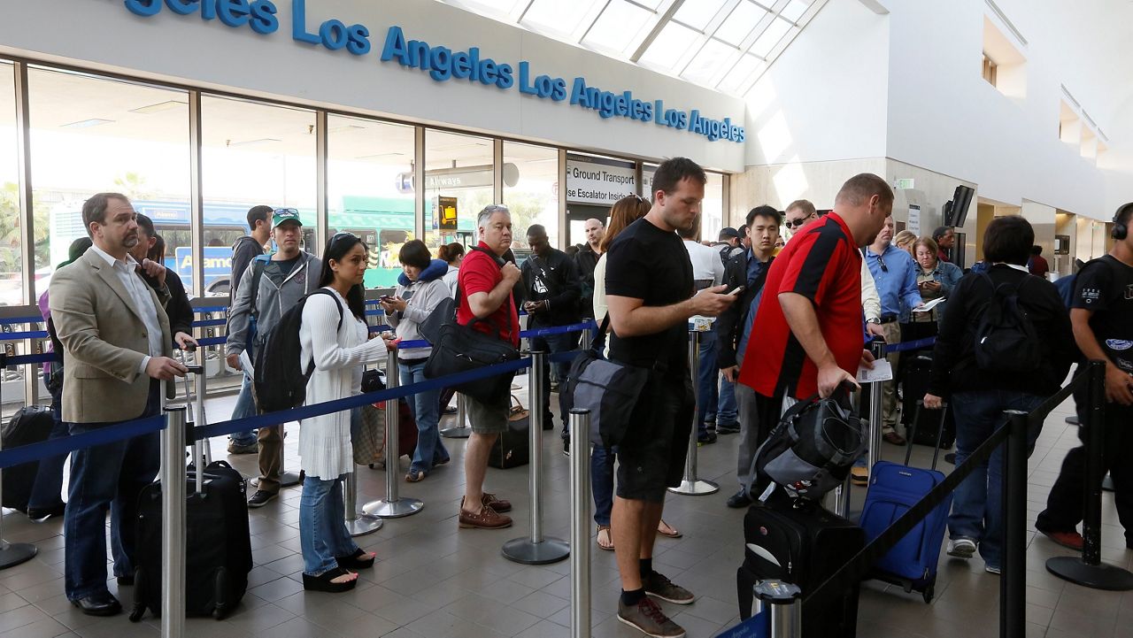 Travelers stand on line at LAX International Airport in Los Angeles on April 22, 2013. (AP Photo/Damian Dovarganes)