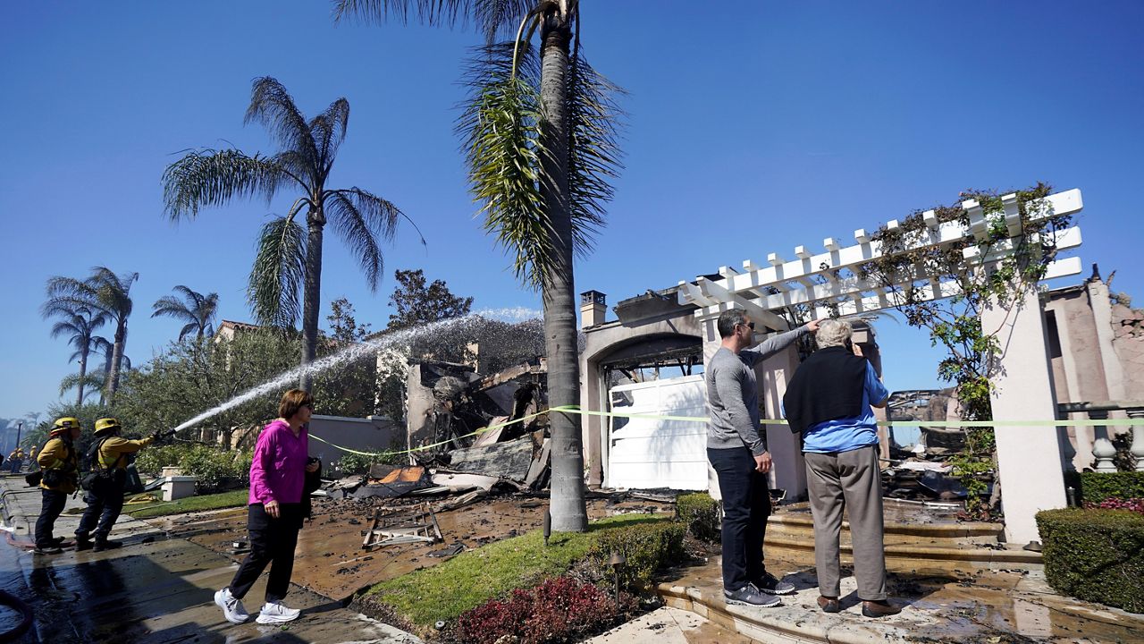 Residents take a close look at their fire-ravaged home as fire crews douse hot spots in the aftermath of the Coastal Fire on May 12, 2022, in Laguna Niguel, Calif. (AP Photo/Marcio Jose Sanchez)