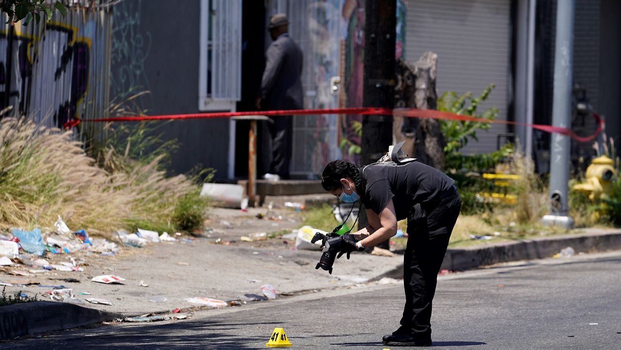 A Los Angeles Police field forensic photographer documents evidence after a shooting at a warehouse party in LA. (AP Photo/Damian Dovarganes)