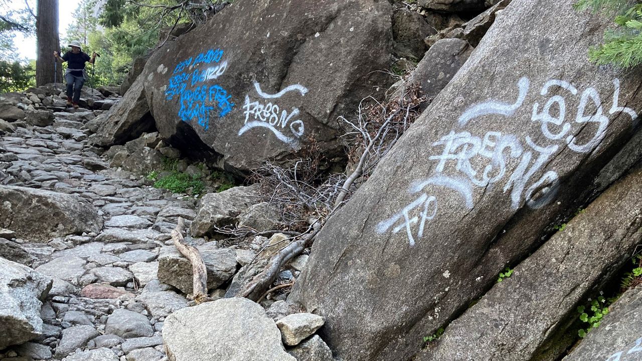 In this photo released Sunday by the National Park Service, a hiker walks down a graffiti covered trail in Yosemite National Park, Calif. (National Park Service via AP)