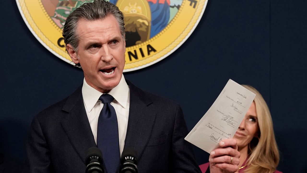 California Gov. Gavin Newsom displays a bill he signed that shields abortion providers and volunteers in California from civil judgements from out-of-state courts during a news conference Friday in Sacramento, Calif. (AP Photo/Rich Pedroncelli)