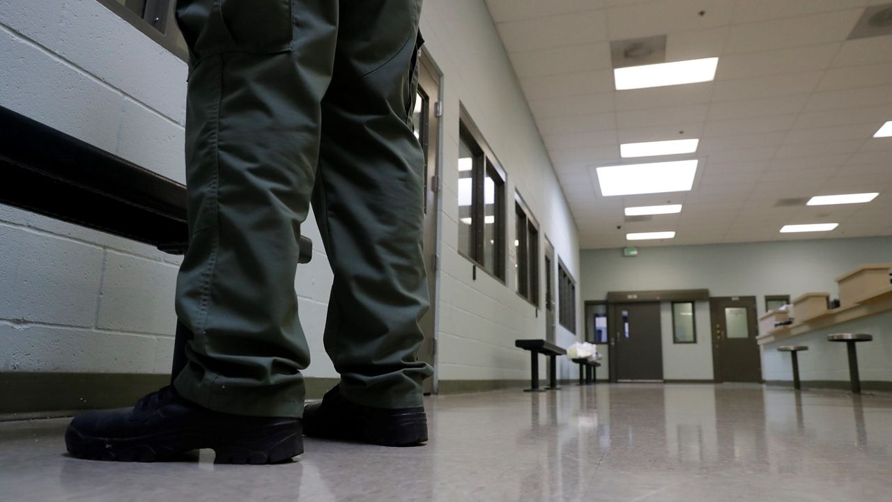 In this Aug. 28, 2019, file photo, a guard stands in the intake area at the Adelanto ICE Processing Center in Adelanto, Calif. (AP Photo/Chris Carlson)