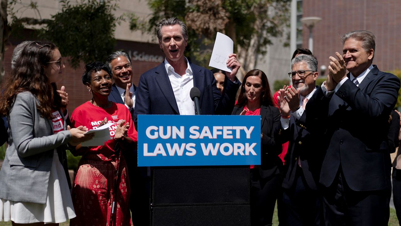 California Gov. Gavin Newsom, center, celebrates after singing a gun control law as he is surrounded by state officials including state Sen. Bob Hertzberg, right, state Sen. Anthony Portantino, second right, Attorney General Rob Bonta, third left, and gun violence survivors, Mia Tretta, and Arvis Jones, Friday at Santa Monica College in Santa Monica, Calif. (AP Photo/Jae C. Hong)