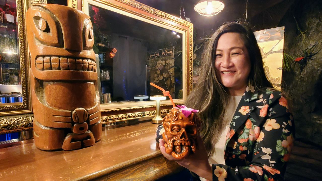 Ying Chang, the co-founder of Strong Water Anaheim, holds up a tiki mug (Spectrum News/Joseph Pimentel)