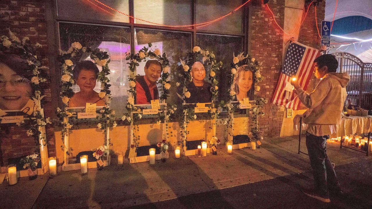 Eric Sham visits a makeshift memorial on Tuesday for those killed in a mass shooting at The Star Ballroom Dance Studio in Monterey Park. (Sarah Reingewirtz/The Orange County Register via AP)