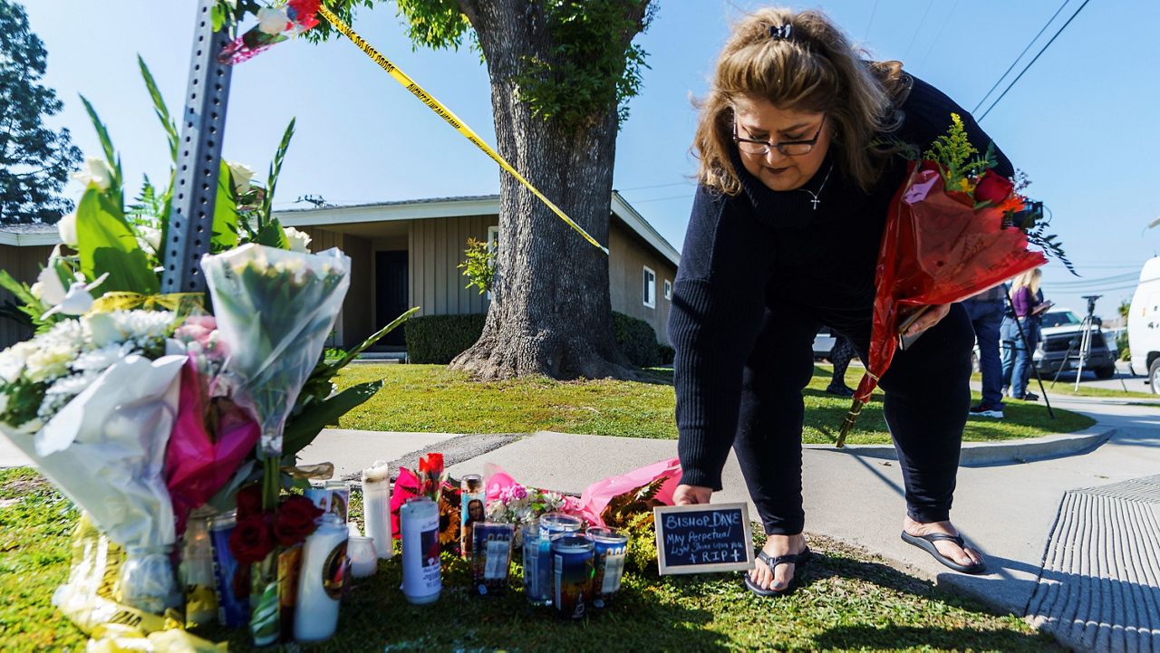 Ramona Torres brings flowers and a framed message Sunday to pay her respects to Bishop David O’Connell near his home in Hacienda Heights, Calif. (AP Photo/Damian Dovarganes)