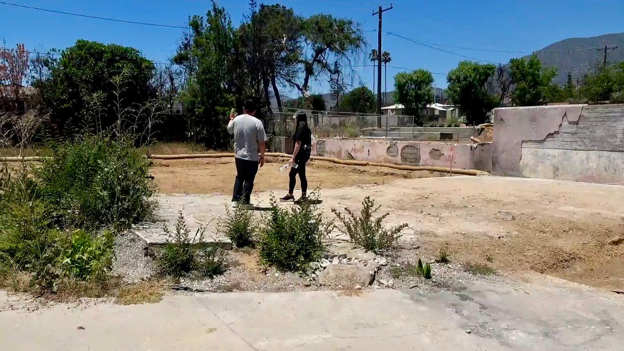 Chien and Kim Yu stand on the lot of what was their home in Altadena. (Spectrum News/Jo Kwon)