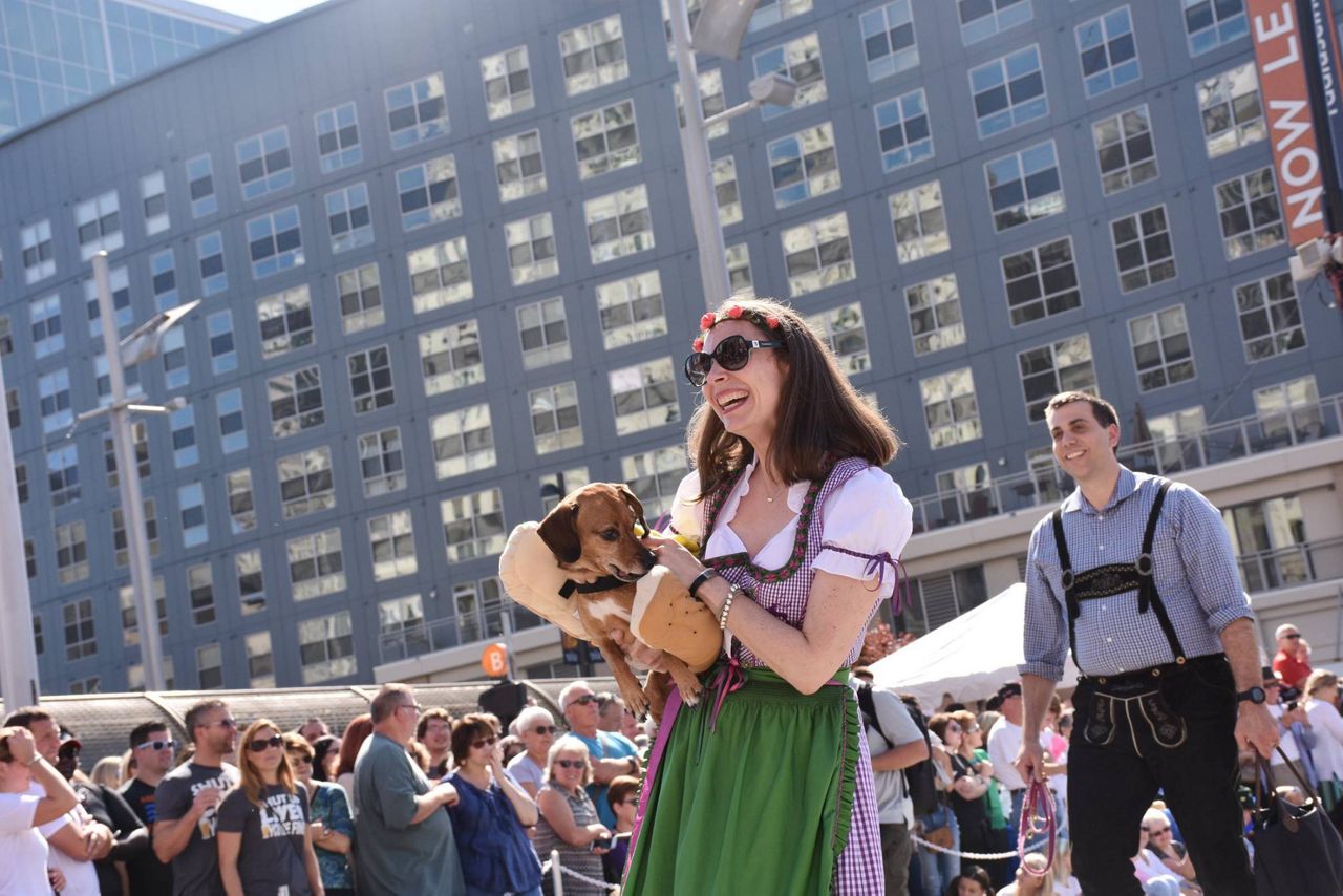 A woman in a dirndl carries a dachshund in a hot dog costumer at Oktoberfest Zinzinnati (Casey Weldon | Spectrum News 1)
