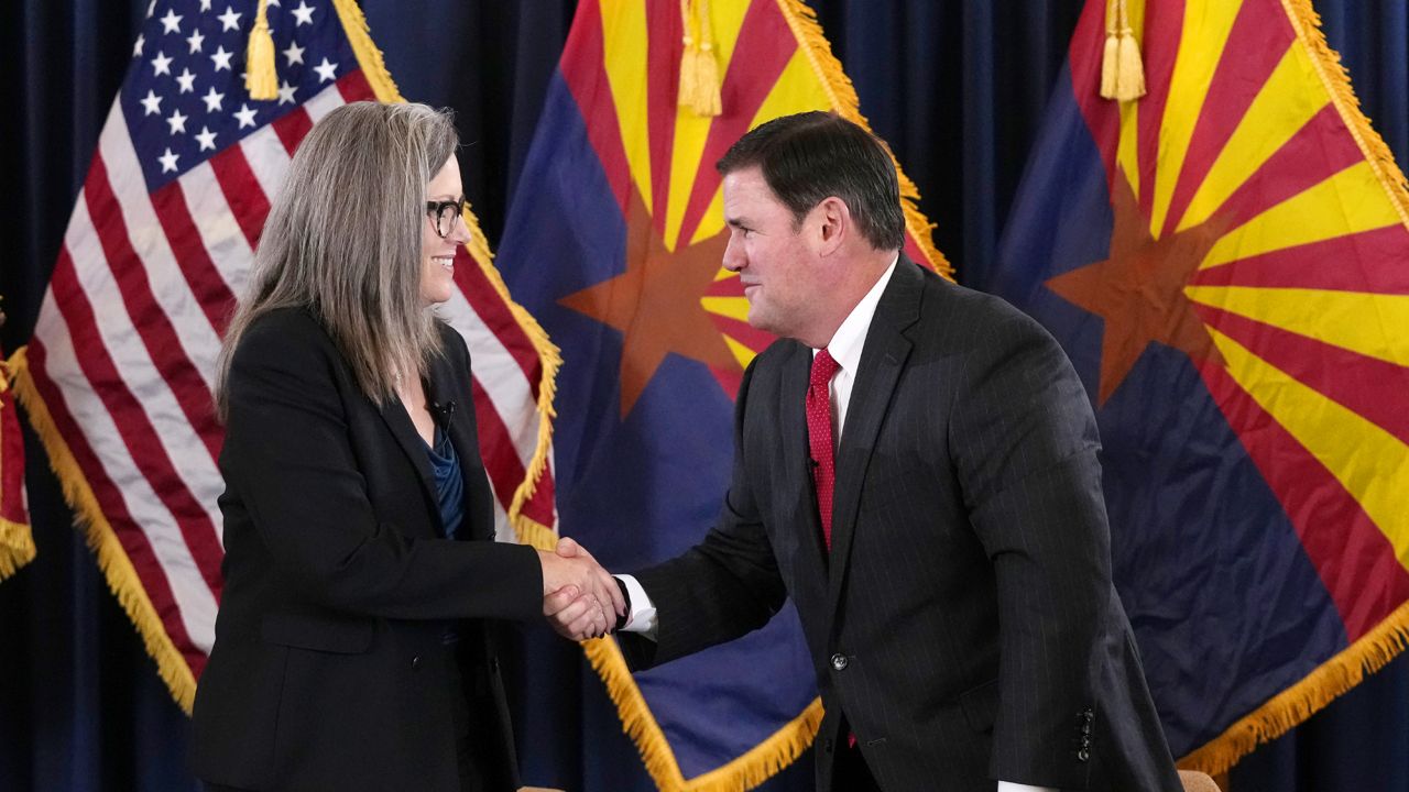 Katie Hobbs, the Democratic governor-elect and current secretary of state, left, shakes hands with Arizona Republican Gov. Doug Ducey, right, after the official certification for the Arizona general election canvass in a ceremony at the Arizona Capitol in Phoenix, Monday, Dec. 5, 2022. (AP Photo/Ross D. Franklin, Pool)