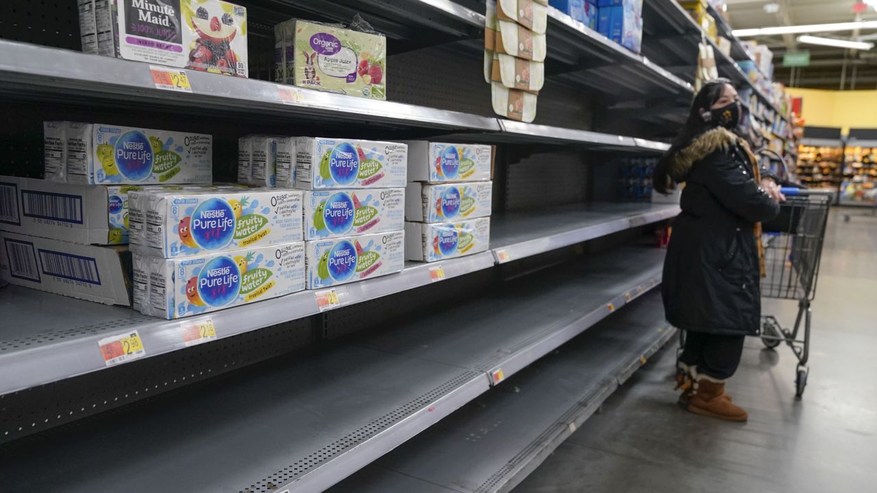 FILE: A woman looks over shelves, some of which are empty, at a Walmart store in Teterboro, N.J., on Jan. 12, 2022. (AP Photo/Seth Wenig, File)