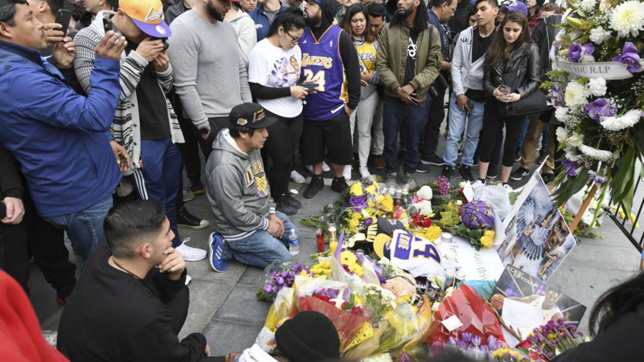 People gather at a memorial near Staples Center after the death of Laker legend Kobe Bryant Sunday, Jan. 26, 2020, in Los Angeles. (AP Photo/Michael Owen Baker)