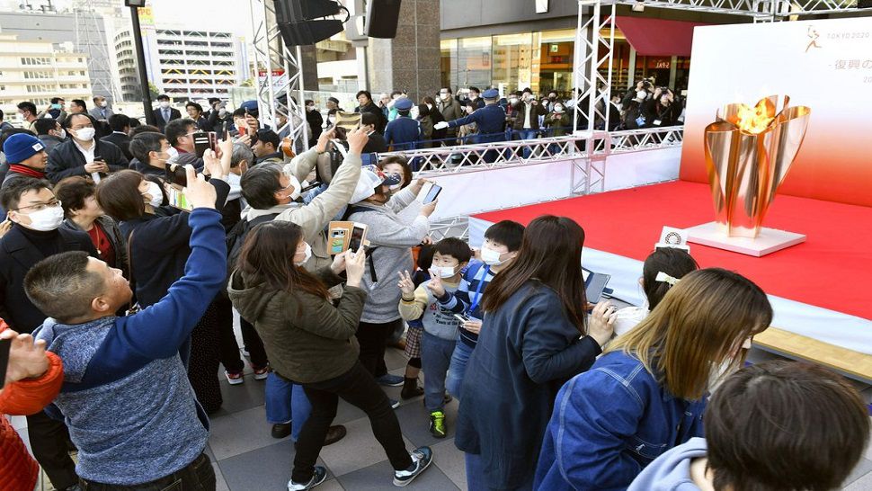 People gather to look at the Olympic flame on display in Sendai, Miyagi prefecture, north of Tokyo on Saturday.  The Olympic flame arrived from Greece on Friday, and the flame will be on public display in areas affected by the 2011 earthquake and tsunami, prior to the Olympic torch relay.  (Kyodo News via AP)