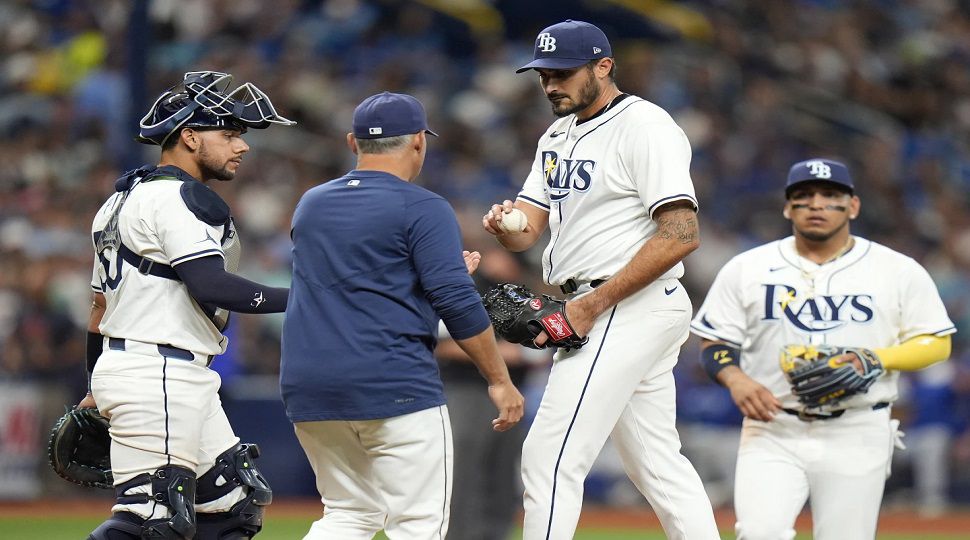 Tampa Bay Rays starting pitcher Zach Eflin, second from right, hands the ball to manager Kevin Cash, second from left, after being taken out of the game against the Toronto Blue Jays during the sixth inning of a baseball game Thursday, March 28, 2024, in St. Petersburg, Fla. looking on is catcher Rene Pinto, left, and third baseman Isaac Paredes, right. (AP Photo/Chris O'Meara)