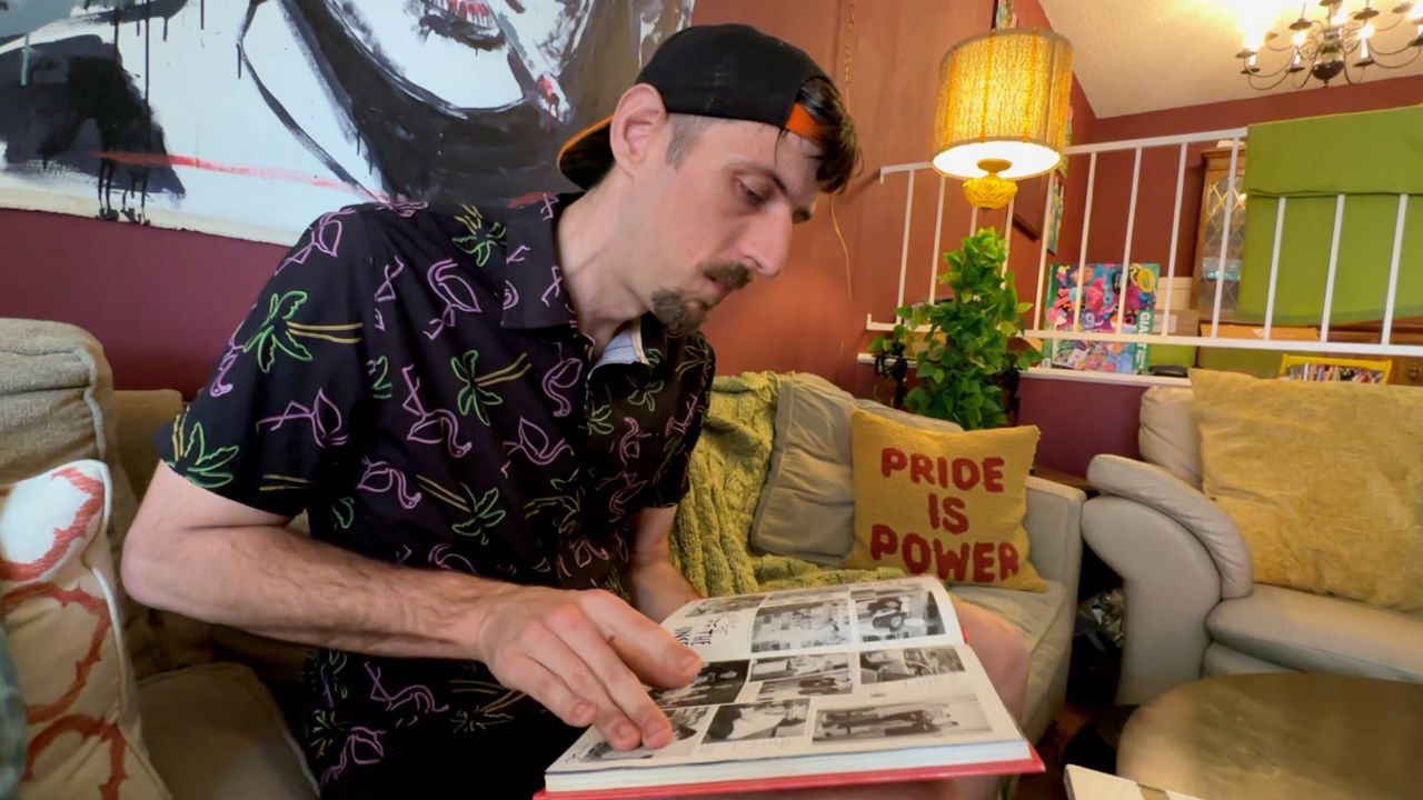 Fort Worth resident Matthew Kistler looks at his high school yearbook. Growing up in a small town in he was scared to come out as gay as a teenager. (Spectrum News 1/Lupe Zapata)