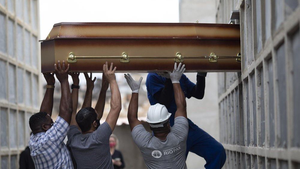 FILE - In this April 13, 2021, file photo, the remains of a woman who died from complications related to COVID-19 are placed into a niche by cemetery workers and relatives at the Inahuma cemetery in Rio de Janeiro, Brazil. (AP Photo/Silvia Izquierdo, File)