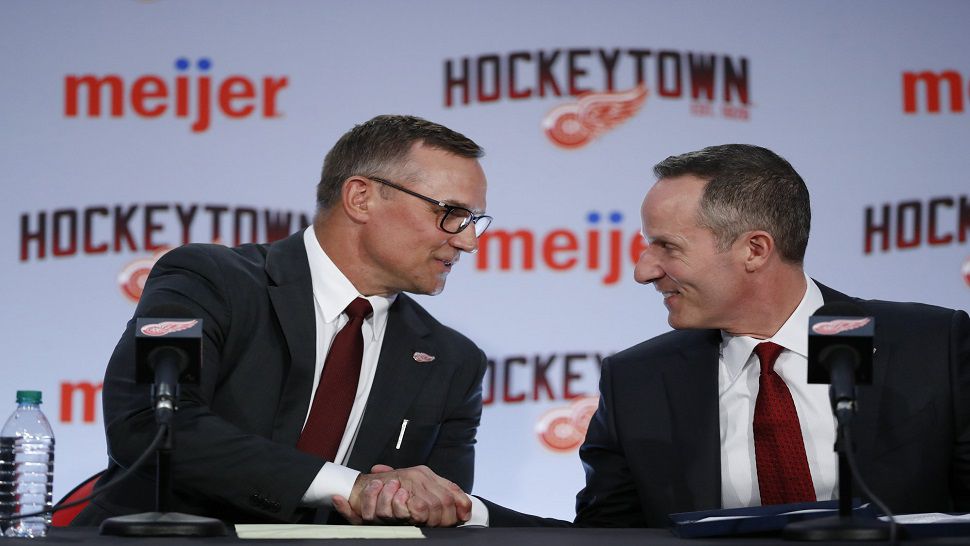 Steve Yzerman, left, shakes hands with Christopher Ilitch, president and CEO of Ilitch Holdings, Inc., which owns the Detroit Red Wings.  Yzerman was introduced as the team's new GM on Friday.  He previously served as the General Manager of the Tampa Bay Lightning from 2010 to 2018.  (AP Photo/Carlos Osorio)