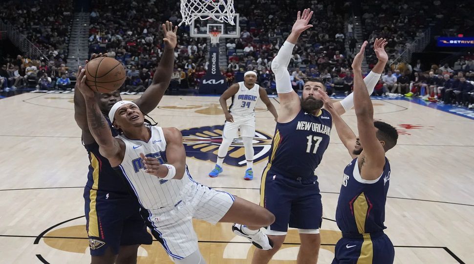 Orlando Magic forward Paolo Banchero (5) goes to the basket between New Orleans Pelicans forward Zion Williamson, center Jonas Valanciunas (17) and guard CJ McCollum, right, in the first half of an NBA basketball game in New Orleans, Wednesday, April 3, 2024. (AP Photo/Gerald Herbert)