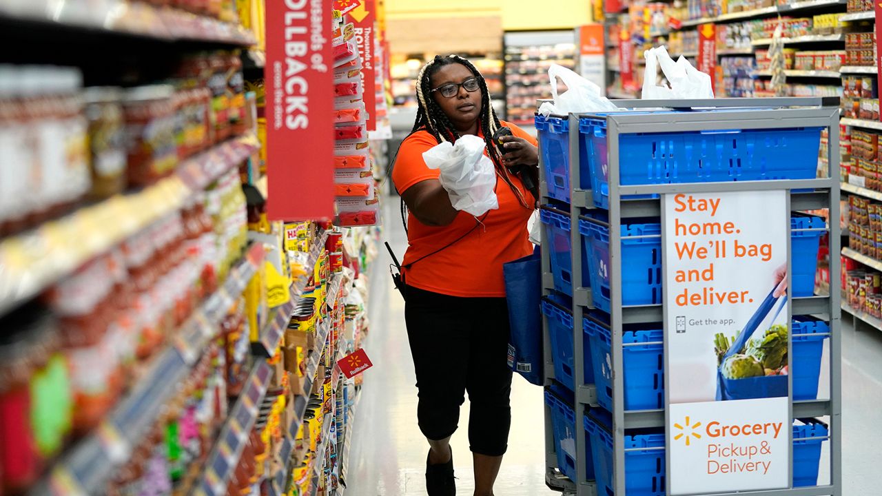 An image of a Walmart grocery employee stacking items into a cart for online pickup/delivery options (Spectrum News/File)