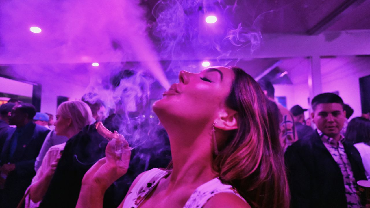 A guest takes a puff from a marijuana cigarette at the Sensi Magazine party celebrating the 420 holiday in the Bel Air section of Los Angeles, April 20, 2019. (AP Photo/Richard Vogel, File)